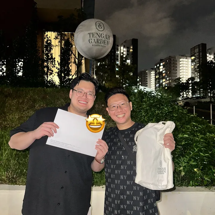 Davis and his buyer outside the Tengah Garden Residences sales gallery at night, holding the booking documents
